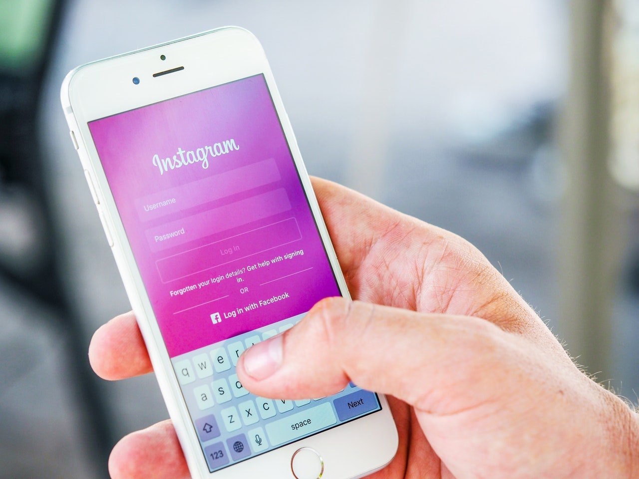 A hand holding an iphone with the Instagram login page displayed