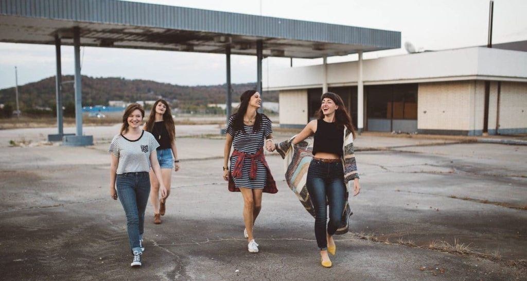 four teenage girls walk towards the camera smiling