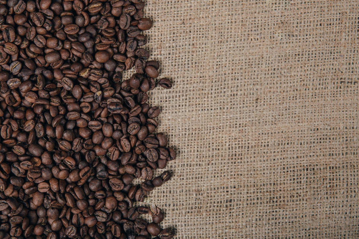 Kaffeebohnen liegen auf einem Jutesack. Wer den Handel mehr schätzt als die Arbeit in der Küche kann sich mit einer Kaffeerösterei selbstständig machen.