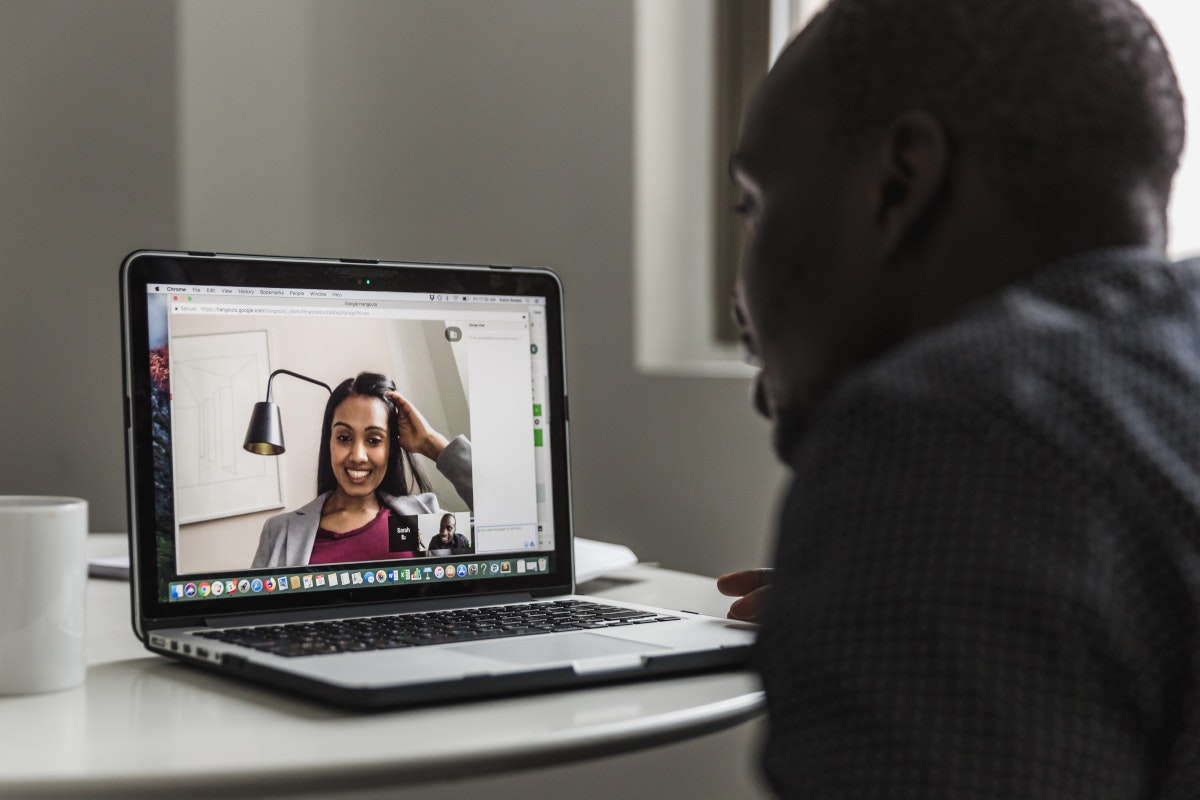 Ein junger Mann sitzt vor einem aufgeklappten Laptop mit offenem Videochat und spricht mit einer jungen Frau. Remote Work macht viele Arbeiten ortsunabhängig. Selbstständig machen Idee Nummer 5: Die eigene Online-Marketing-Agentur.