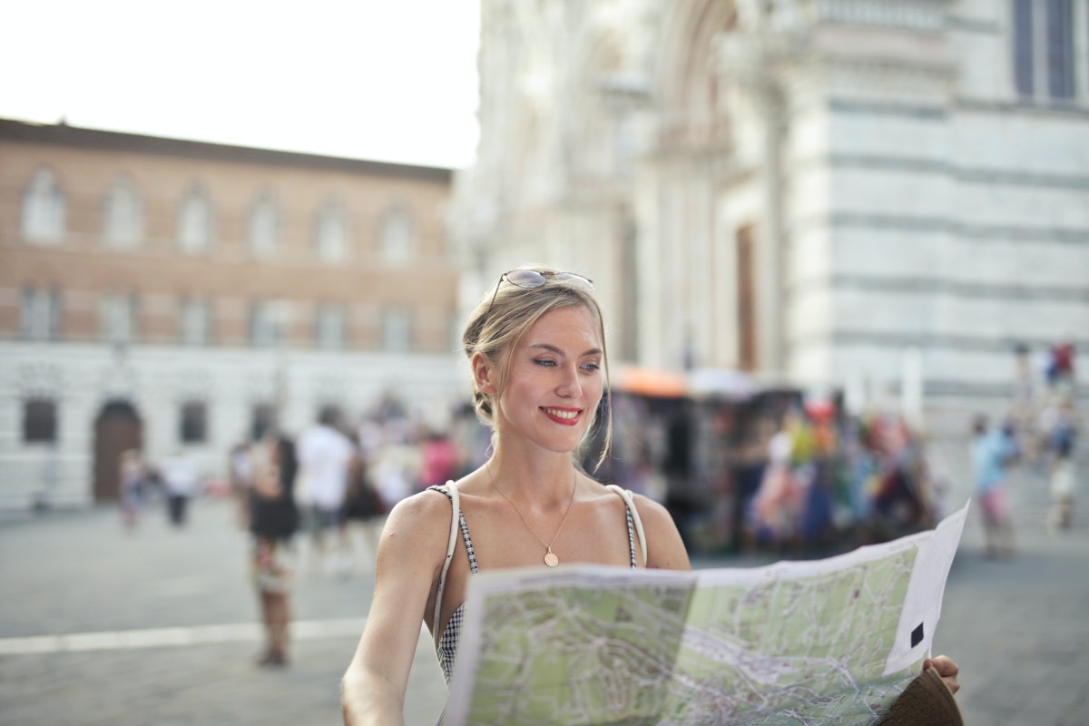 Eine junge Frau hält einen Stadtplan in den Händen. Selbstständig machen Idee Nummer 21: Tour Guide werden.