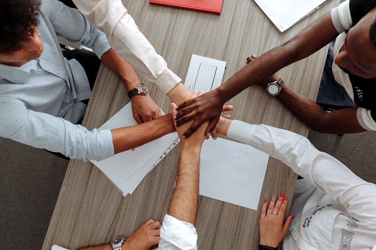 Selbstständig machen ohne eigenkapital. Ein Team hält Hände als Symbol für Teamarbeit und Kollaboration bei der Gründung.